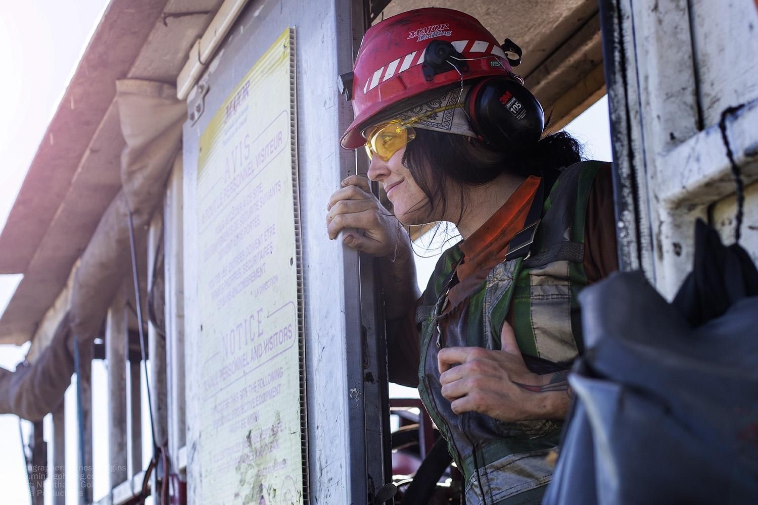 Major Drilling employee looking out of a drill shack wearing full PPE